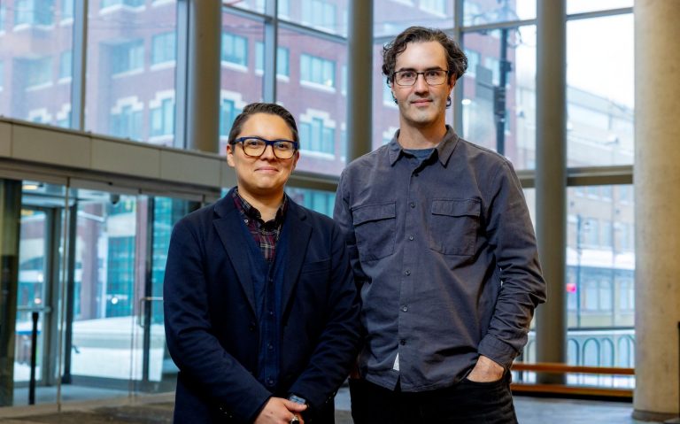 Two researchers stand in the atrium of a building
