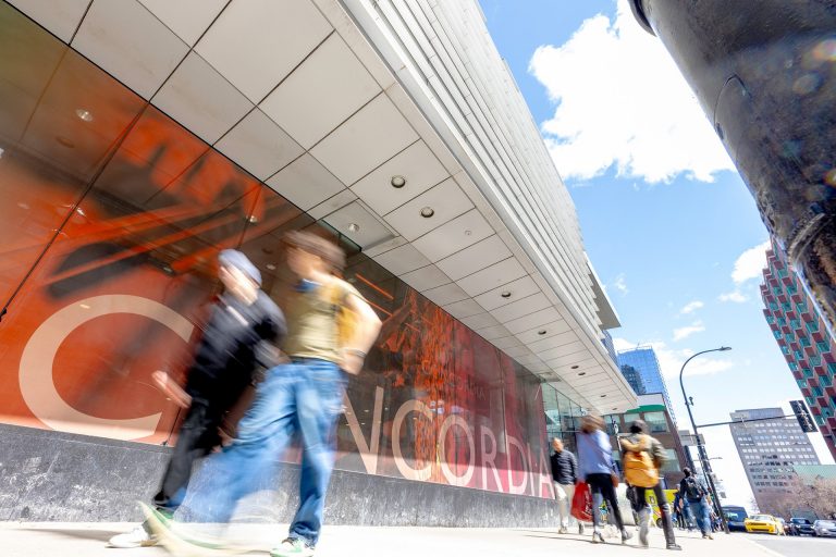 Photo of people blurred in motion on a city street.