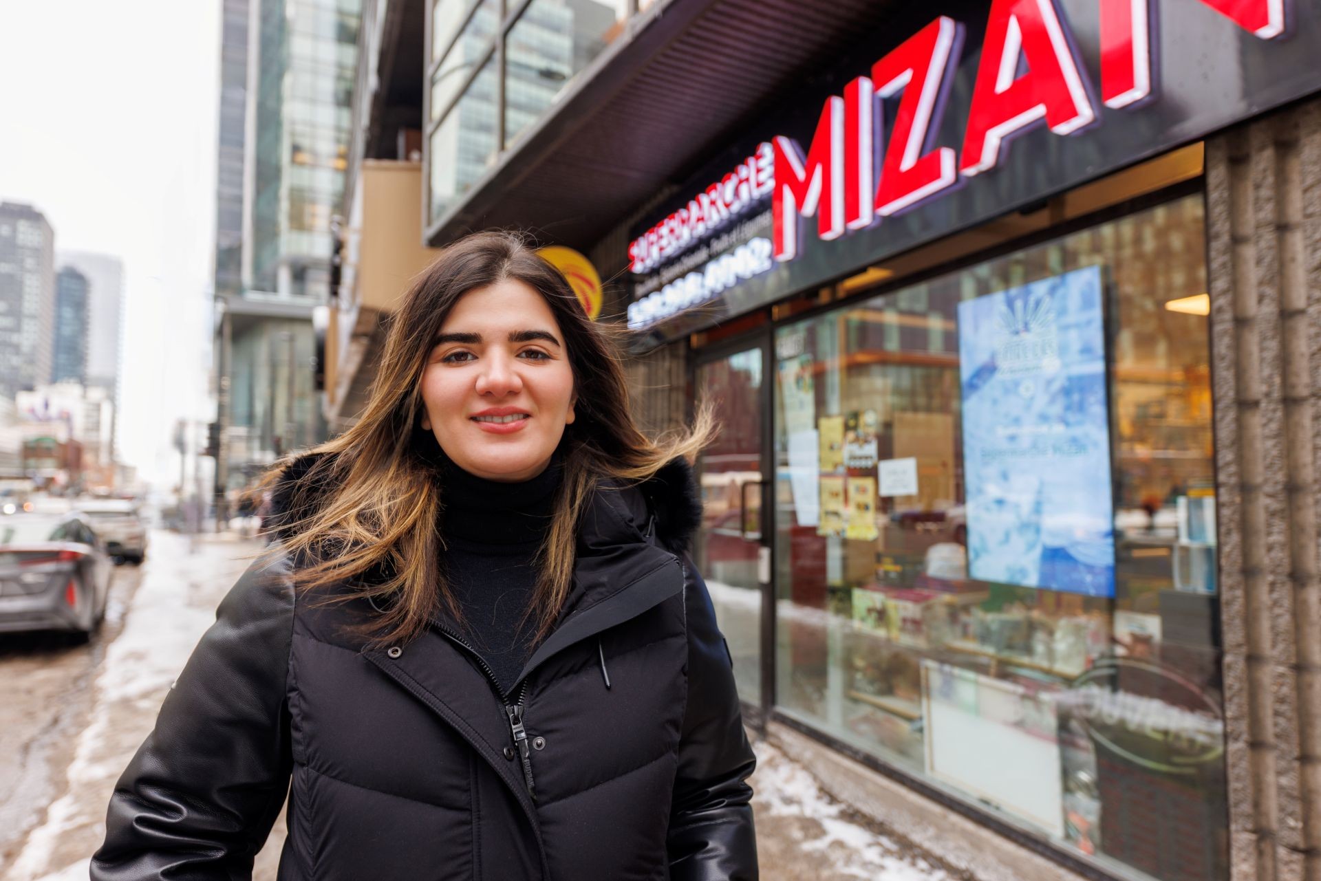 Une femme se tient devant une épicerie dans une rue de la ville.