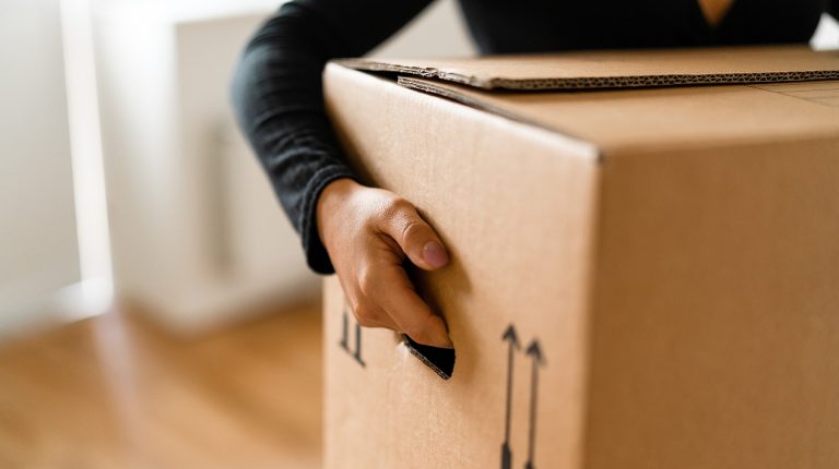 View from the shoulders down of a person holding a cardboard box