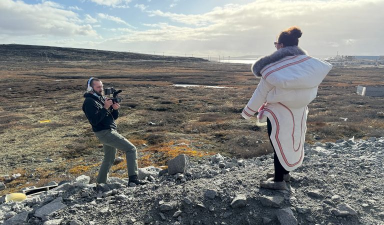 Un jeune homme en train de prendre une photo d'une femme sur un affleurement rocheux, avec un barrage en arrière-plan