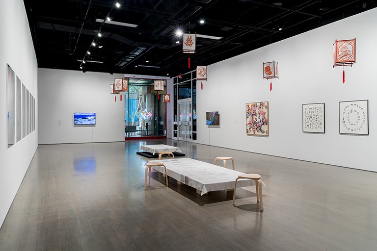 Vue d'un espace d'exposition artistique, avec un sol en béton et des œuvres accrochées aux murs