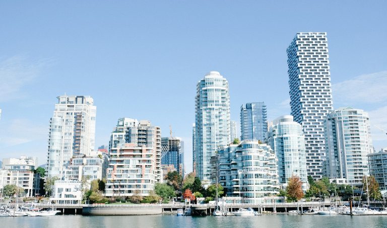 Image of a city on the water — white, grey and pink buildings in an urban setting.