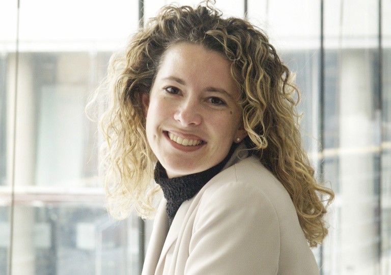 Young, smiling woman with long, curly, blonde hair.