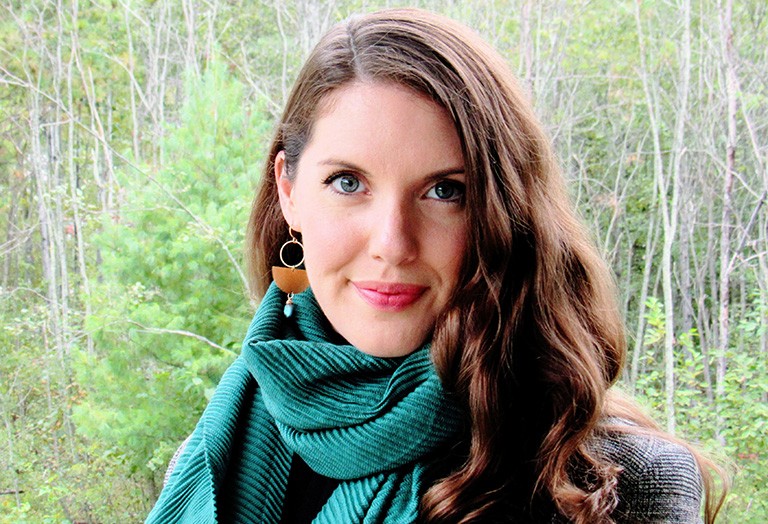 A young woman with long, brown hair, and a green scarf around her neck.