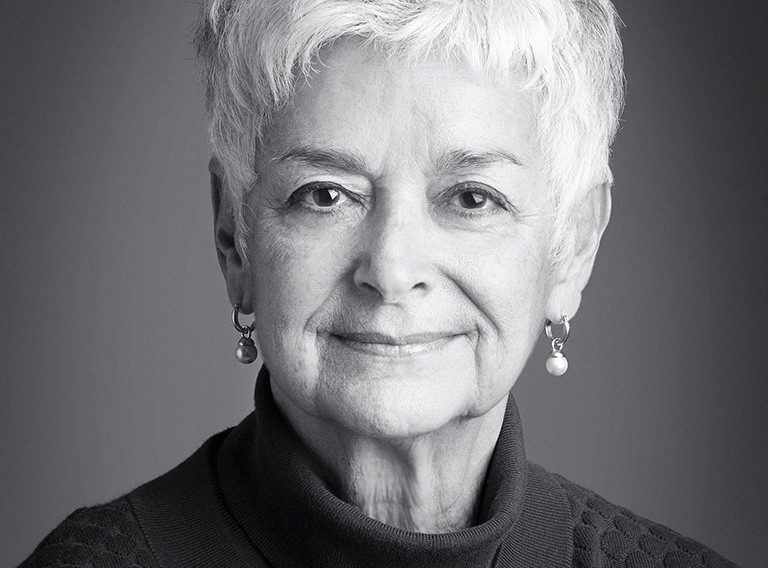 Black and white photo of an older woman with short silver hair and a black knit sweater.