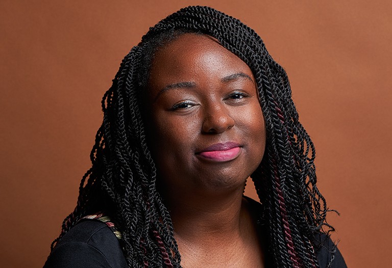 Young, smiling Black woman with braids and a black top.