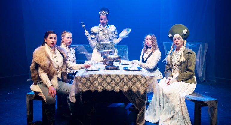 A group of seated people in costume, for a play in the theatre.