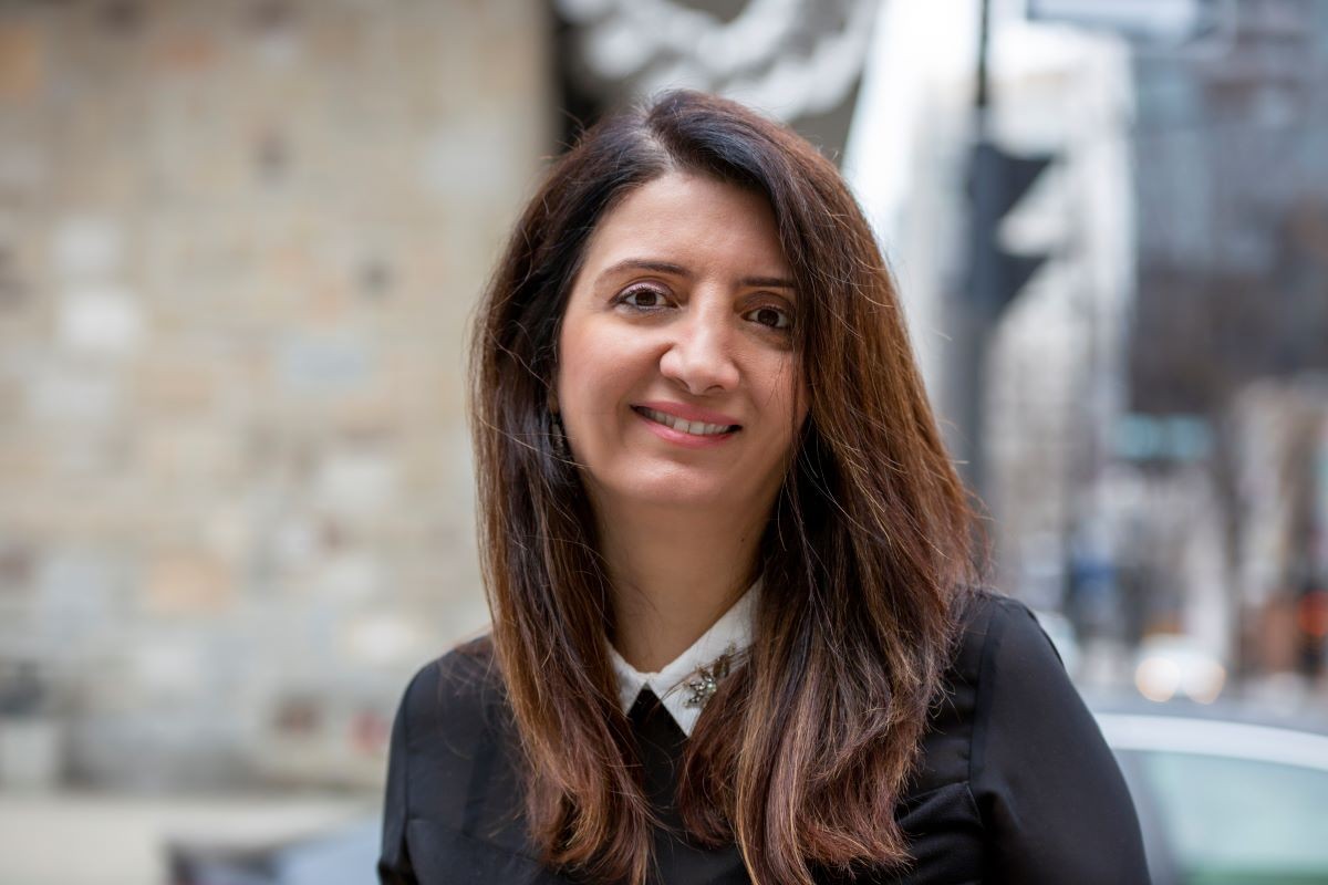 Portrait of Suzan Ali, a young smiling woman with long dark hair.