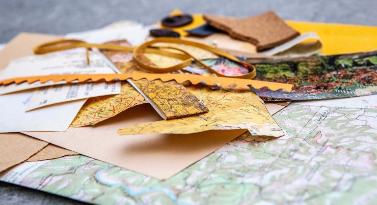 Objects on a table, including a map, a ruler, and other found pieces.