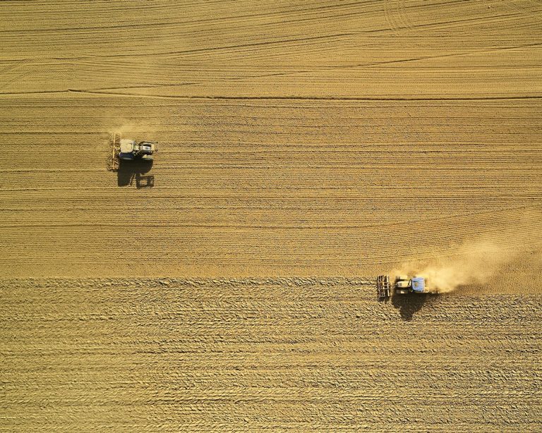 Two tractors tilling a field
