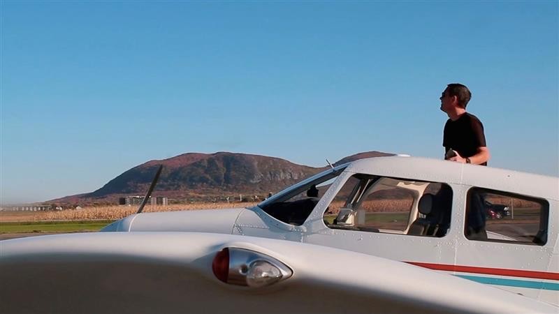 Man standing in the door of a small aeroplane.