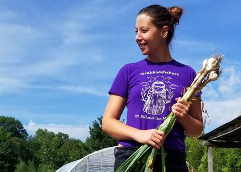 Young woman with long, dark hair, holding a bunch of onion stems.