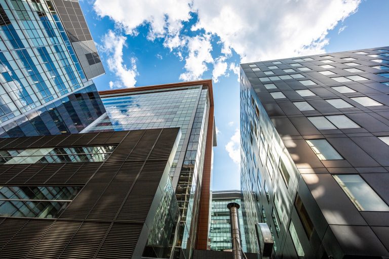 modern city buildings with bright blue sky and white clouds in the background