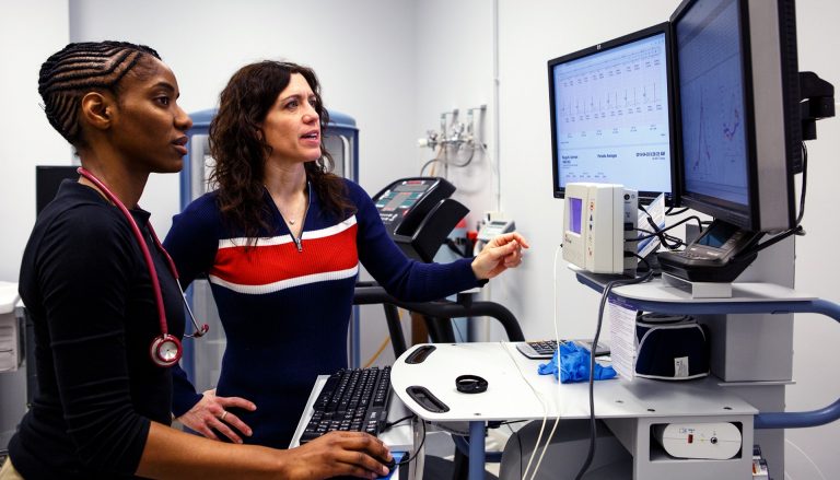 Two women in a lab, looking at figures on a computer screen.