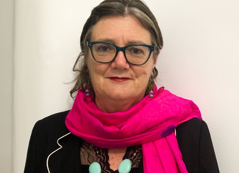 Margaret Brehony: “Research on Irish migration in the Hispanic world of the Americas is a growing field of Irish Studies.” Older woman with dark-rimmed glasses, blonde hair, a pink scarf and a black suit jacket.