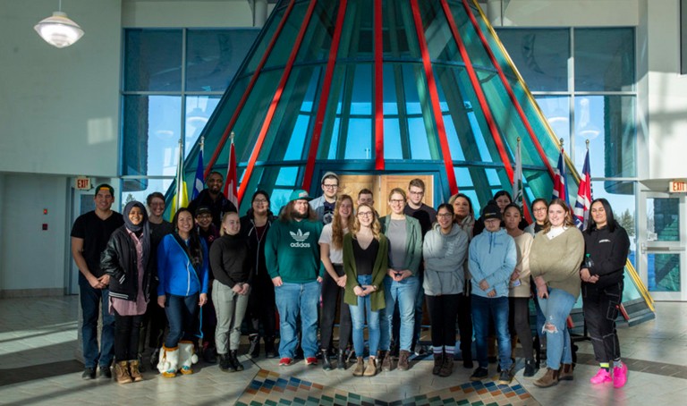 A large group of students standing together for a photograph in an atrium.