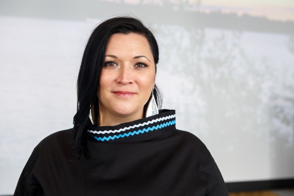 Heather Igloliorte: “We want Inuit to see this is an exhibition that is for them.” Young, smiling woman with long, dark hair, large silver earrings and a black top with a high collar.