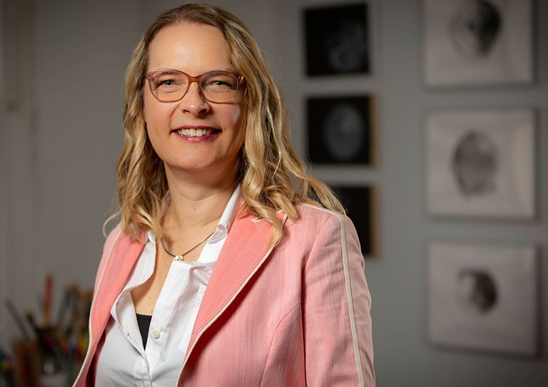 Blonde woman with glasses, pink jacket, white shirt