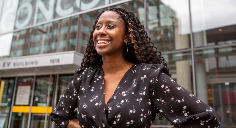 Young, smiling Black woman with long, curly hair and a patterned shirt.