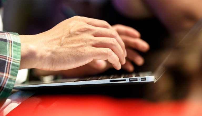 Hands typing on a laptop