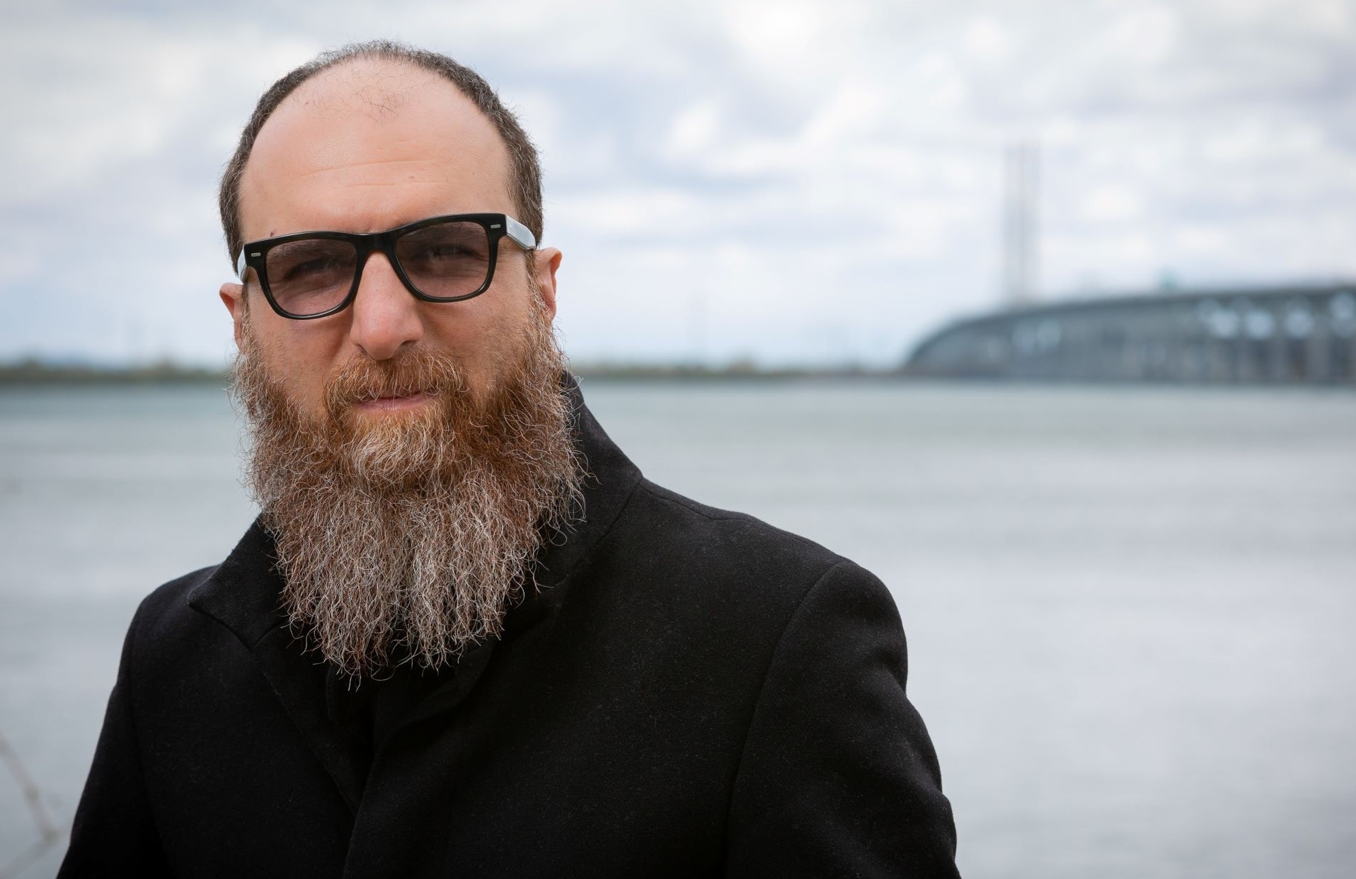 Bearded man in dark glasses standing by the St. Lawrence River