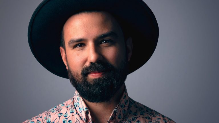 Portrait of man with hat wearing collared shirt with floral pattern.