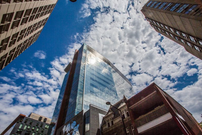 Looking up at a downtown high-rise with the sun glinting off the upper windows