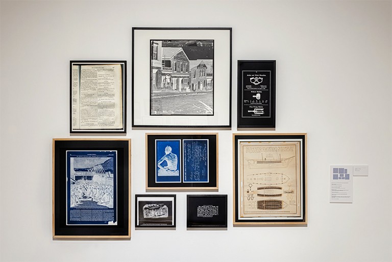 Black Drones in the Hive, Chapter 3 – Slave Trade, by Deanna Bowen, 2020. | Photo by Toni Hafkenscheid An art installation: Images in frames on a wall.