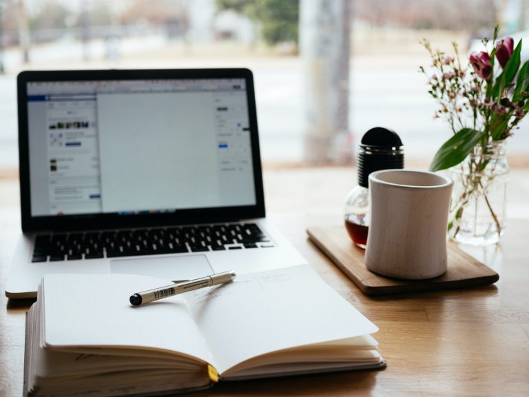 Laptop, open notebook with pen and mug