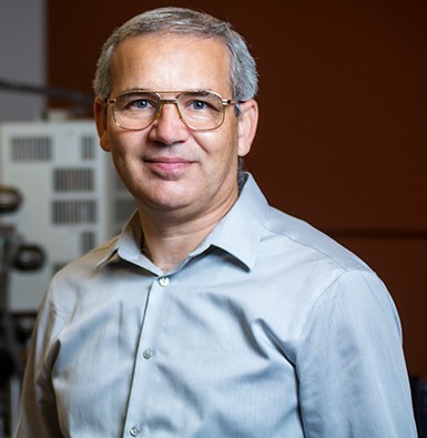 Dmytro Kevorkov Man with greying, short hair, glasses and a grey shirt.