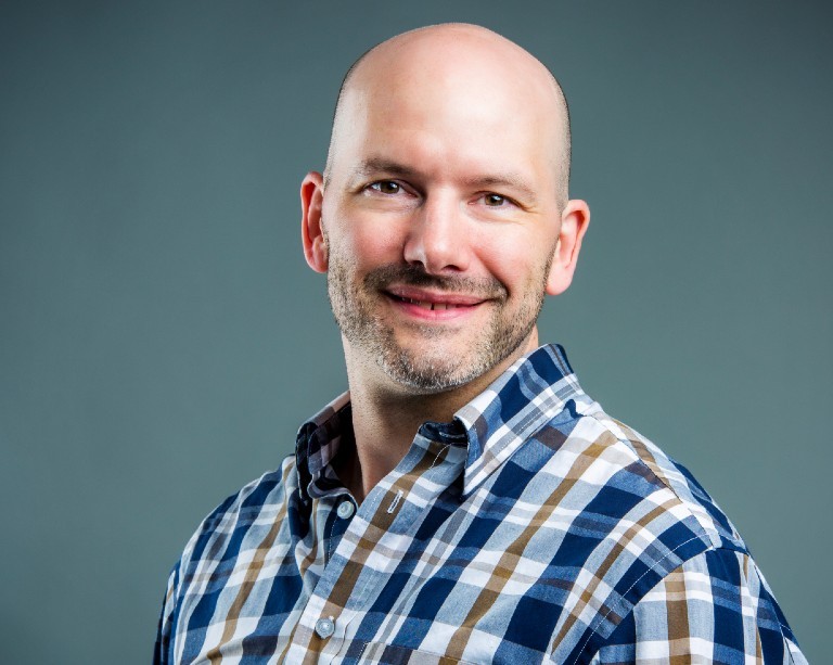 Smiling man in blue brown and white striped shirt