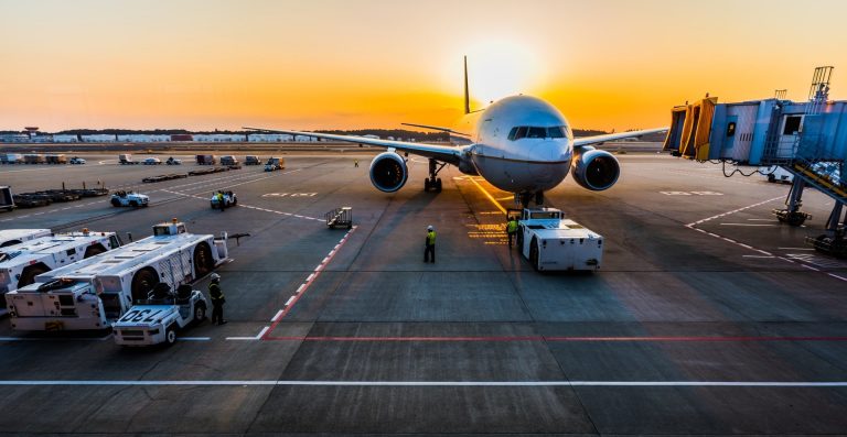 Grey airplane parked at gate during sunset