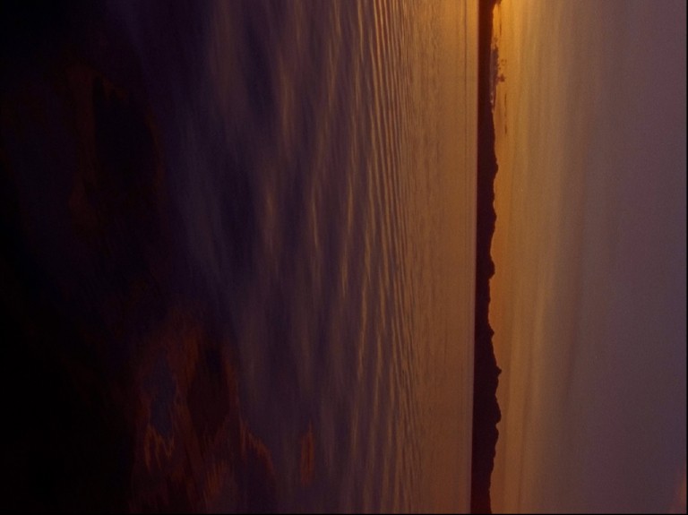 Closeup of still body of later with landscape out of focus in background at sunset