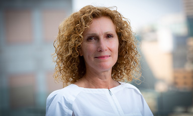Smiling woman with long, curly red hair and a white shirt.