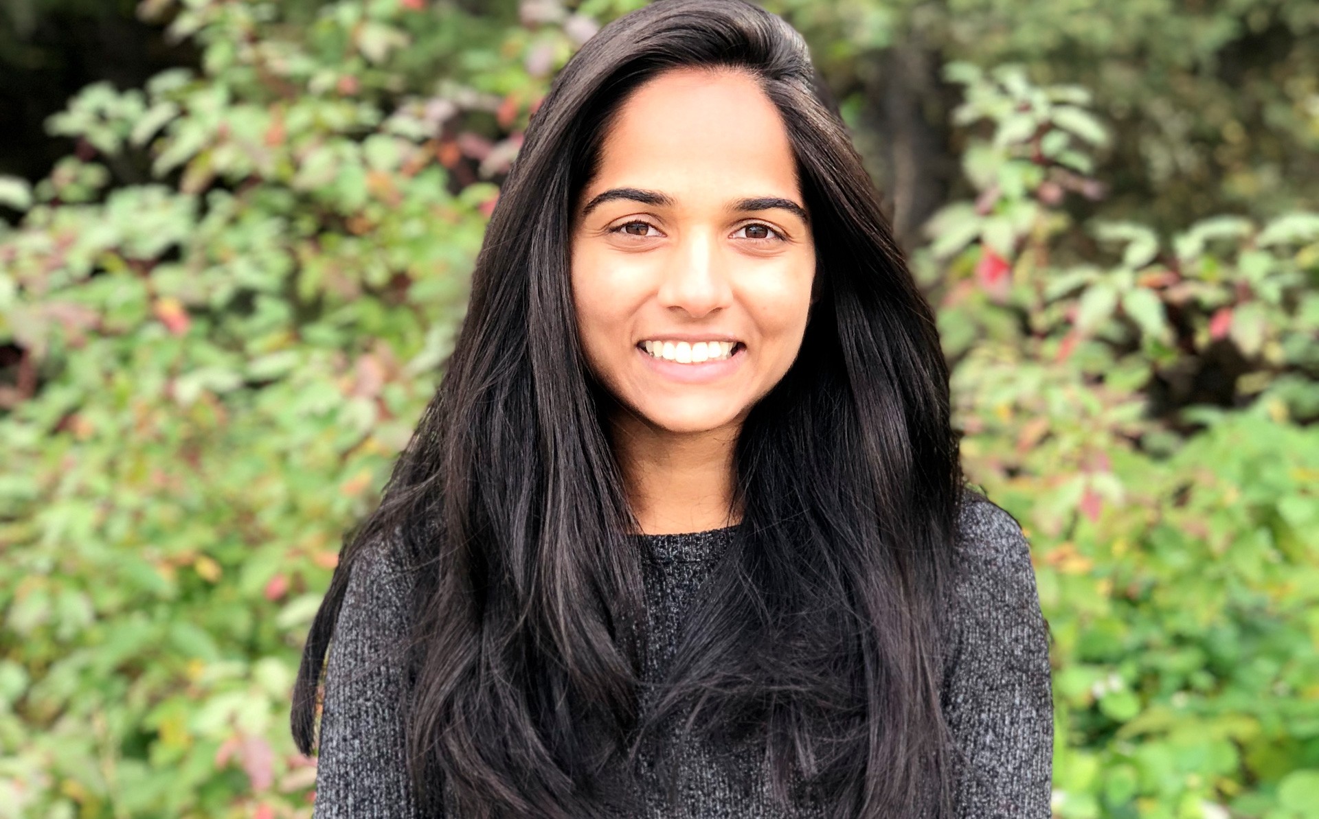 PhD candidate Twinkal Patel Young, smiling woman with long, dark hair and a grey top.