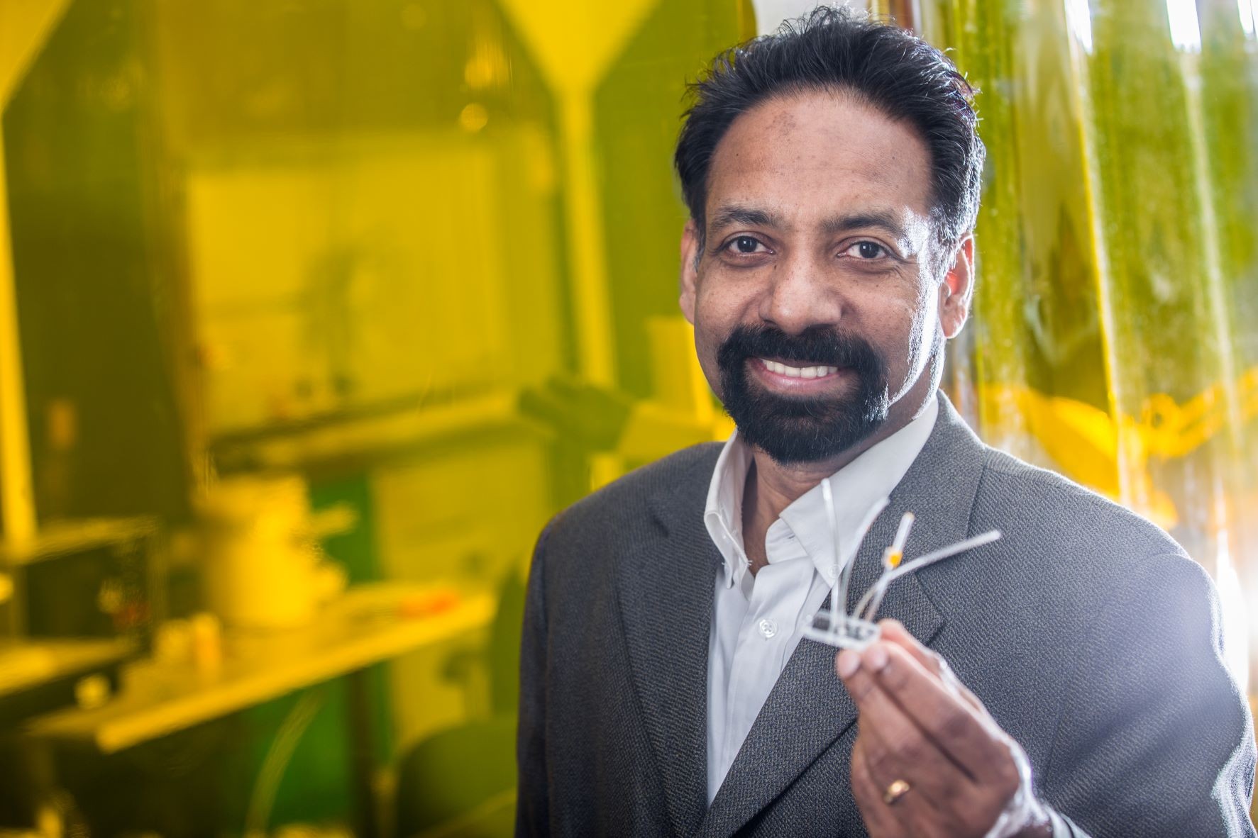 Muthukumaran Packirisamy holding a microfluidics device