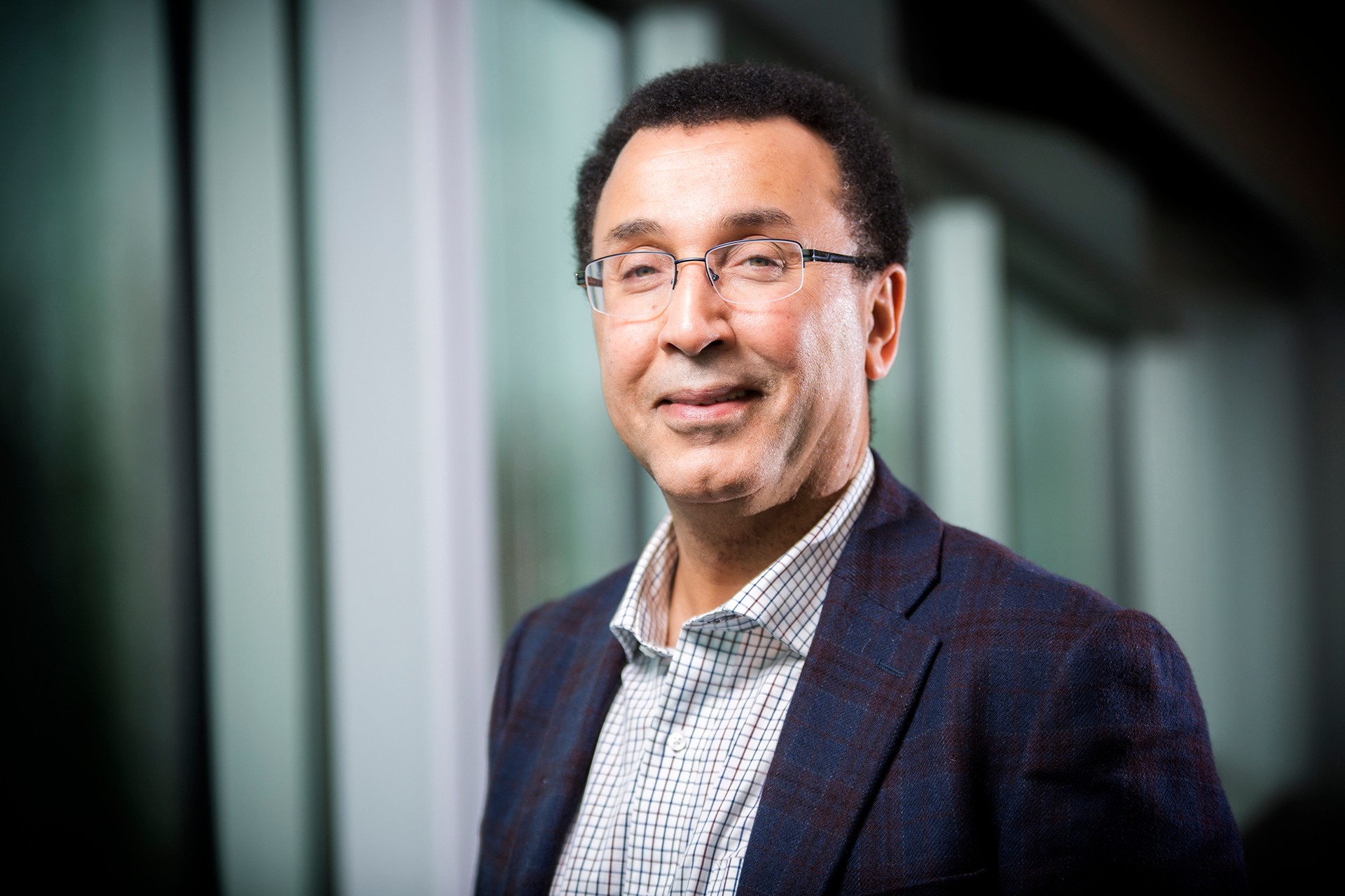 Habib Benali: “If we really want to have an impact on society, we should go to society.” Smiling man with glasses and short, dark, curly hair, a dress shirt and jacket.