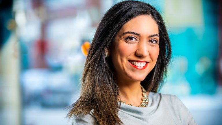 Young, smiling woman with long dark hair and brown eyes.