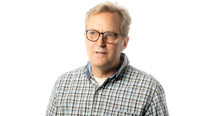 Image of a middle-aged man with short, blonde hair, in a checkered shirt and in the process of saying something