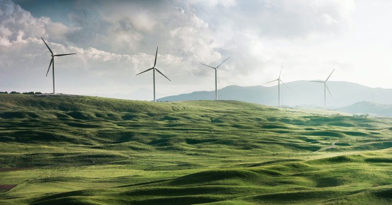 Image of rolling hills with large wind turbines spread out across them.