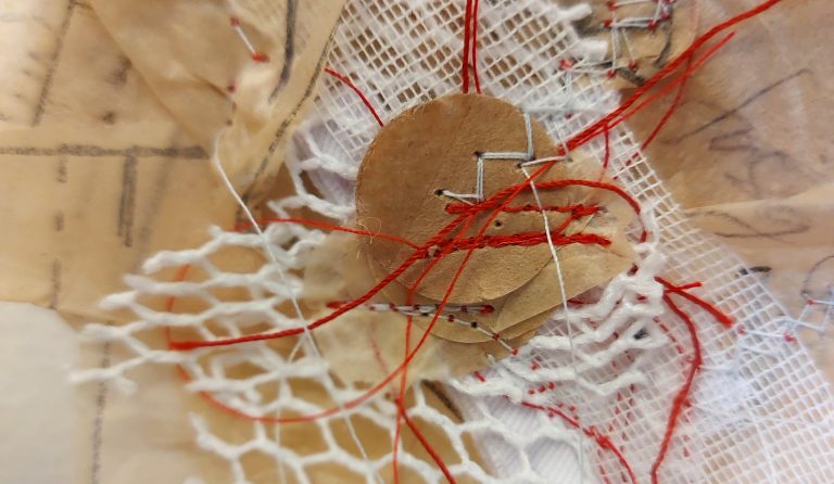 Mixed media — paper, mesh, cardboard — sewn with red thread to a piece of paper.
