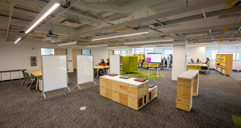 A carpeted open space with bookshelves and students working at desks