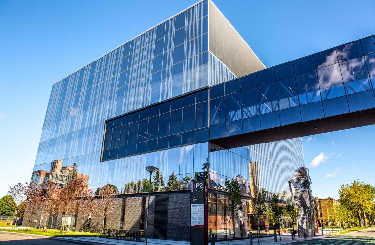 Picture of a building made entirely out of glass windows, with a glass tunnel reaching from the building to out of the picture frame.