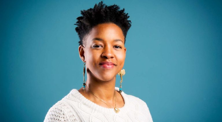 Smiling Black woman with short, dark hair, dangling earrings and a white knit top.