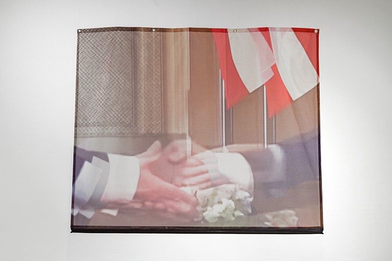 Image of a photo of a tv screen with two people shaking hands.