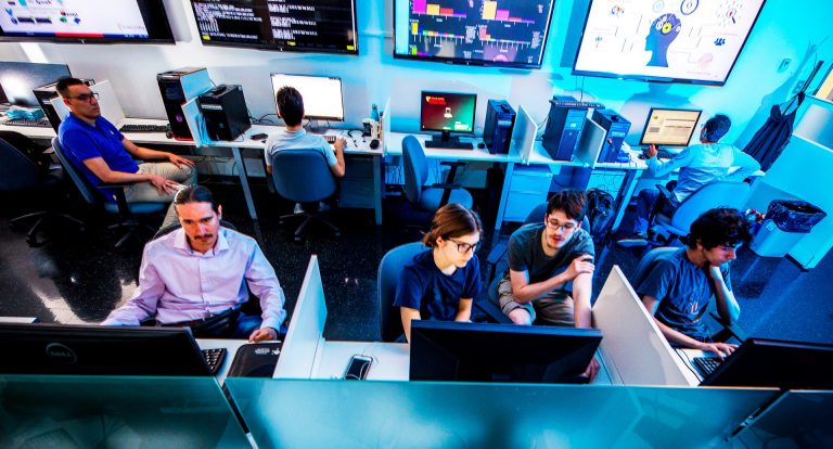 A group of people seated at computer terminals in a university classroom.