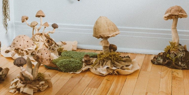 Art display of constructed mushrooms and flora on hardwood floor