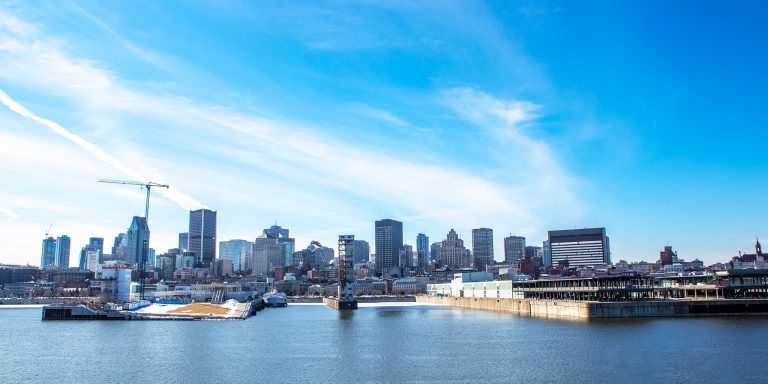 Image of a city from a distance with a river in the foreground.