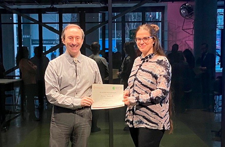 Middle-aged gentleman giving a certificate to a young smiling woman with glasses.